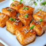 - 1 lb salmon fillet, skin removed and cut into bite-sized cubes - 1/4 cup teriyaki sauce - 1 tablespoon sesame oil - 1 tablespoon honey - 1 teaspoon freshly grated ginger - 1 garlic clove, finely minced - 1 tablespoon sesame seeds - 2 green onions, thinly sliced - Cooked jasmine rice or steamed vegetables To make the marinade, I start by grabbing a mixing bowl. I add 1/4 cup of teriyaki sauce, which gives a sweet and savory taste. Then, I pour in 1 tablespoon of sesame oil for a nutty flavor. Next, I add 1 tablespoon of honey to enhance the sweetness. I also grate 1 teaspoon of fresh ginger and mince 1 garlic clove, adding both to the bowl. Finally, I whisk everything together until it blends well. Now, I take 1 pound of salmon fillet, cut into bite-sized cubes. I gently toss these salmon cubes into the marinade. It’s important to coat each piece well. I cover the bowl and let it sit for at least 15 minutes. This time allows the salmon to soak up all those delicious flavors. While the salmon marinates, I preheat my air fryer to 400°F (200°C). This usually takes about 5 minutes. I lightly spray the air fryer basket with cooking spray to prevent sticking. Once preheated, I carefully arrange the marinated salmon bites in a single layer in the basket. I ensure they are not crowded, as this helps them cook evenly. Next, I air fry the salmon bites for 8-10 minutes. I flip them halfway through cooking to get a golden-brown color on all sides. After cooking, I remove the salmon bites and place them on a serving plate. - Avoid overcrowding the basket: If you pack too much salmon in, it won't cook well. Give each piece space to crisp up and cook evenly. - Adjust cooking time based on cube size: Smaller cubes cook faster. If your salmon pieces are larger, add an extra minute or two. - Use homemade teriyaki sauce: Making your own sauce gives you control over the taste. You can adjust the sweetness or add spices. - Marinate longer for deeper flavor: If you can, let the salmon sit in the marinade for up to an hour. This helps the flavors soak in more. - Carefully remove salmon with tongs: The pieces will be hot. Use tongs to avoid burns when taking them out of the fryer. - Let the air fryer cool before cleaning: This keeps you safe. Wait until it cools down to avoid any burns while cleaning. {{image_4}} You can switch up the flavor by using different marinades. Try an orange glaze for a citrusy kick. Just mix orange juice, soy sauce, and honey. Honey mustard is another great option. Combine honey, mustard, and a splash of vinegar for a sweet and tangy treat. Want to add some veggies to your meal? Bell peppers, broccoli, and snap peas work great with salmon. Chop them into bite-sized pieces. Toss them in the same marinade or season lightly with salt and pepper. Cook them in the air fryer alongside the salmon. This way, you’ll have a full meal in one go. If you need a gluten-free option, make sure your teriyaki sauce is gluten-free. Many brands offer gluten-free soy sauce. You can also make your own. Just mix tamari sauce, honey, and ginger for a tasty, gluten-free teriyaki sauce. This keeps your meal safe and full of flavor. To keep your teriyaki salmon bites fresh, cool them first. Then, transfer the bites to airtight containers. This helps to lock in moisture and flavor. Store them in the fridge for up to three days. When it's time to enjoy leftovers, reheating is key. I recommend using the air fryer. It keeps the salmon bites crispy. Just set it to 350°F (175°C) and heat for 5-7 minutes. If you use a microwave, the salmon might get soggy. For longer storage, you can freeze the salmon bites. Place them in a single layer on a baking sheet. Once frozen, move them to freezer bags. Seal tightly. They can last for up to three months. To defrost, place them in the fridge overnight before reheating. Yes, you can use frozen salmon. Thaw it first for the best results. To thaw, place the salmon in the fridge overnight. If you're short on time, seal it in a bag and run it under cold water for about 30 minutes. After thawing, dry the salmon well before marinating. This helps the marinade stick better. Cooking from frozen may lead to uneven cooking, so thawing is best. You can marinate the salmon for at least 15 minutes. For deeper flavor, marinate it for up to 2 hours. If you marinate too long, the texture might change. Always keep marinating salmon in the fridge to ensure it stays fresh. Teriyaki salmon bites pair well with several sides. I recommend fluffy jasmine rice for a classic touch. Steamed vegetables also add color and nutrients to your plate. For a crunchy contrast, try a fresh salad. You can also serve it with a drizzle of extra teriyaki sauce for more flavor. To sum up, we explored a delicious teriyaki salmon recipe. This dish uses fresh ingredients like salmon, teriyaki sauce, and sesame oil, with a tasty marinade of honey, ginger, and garlic. You learned how to marinate, cook, and serve the salmon perfectly. Remember to use fresh veggies or alternate sauces for fun twists. Store extras properly for later enjoyment. With these tips, you can make a meal that impresses. Enjoy your cooking adventure!