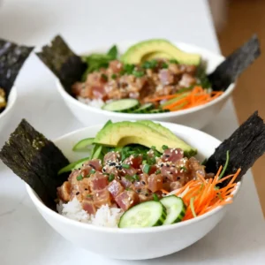 - 1 cup sushi rice - 1 1/4 cups water - 2 tablespoons rice vinegar - 1 tablespoon sugar - 8 oz sushi-grade tuna - 2 tablespoons mayonnaise (Kewpie preferred) - 1 ripe avocado - 1 small cucumber - 1 medium carrot - 1/4 cup green onions - 1 teaspoon sesame seeds - Seaweed sheets (nori) - Soy sauce Gathering fresh ingredients is key. Sushi rice forms the base. It is sticky and perfect for sushi bowls. Rinsing it well helps remove excess starch, making it fluffy. You need sushi-grade tuna for safety and taste. For fresh ingredients, I love ripe avocado. Its creaminess balances the spice. The small cucumber adds crunch. A julienned carrot brings color and sweetness. Green onions add a nice kick. Don't forget garnishes! Sesame seeds add a nice crunch. Nori strips give extra texture. A drizzle of soy sauce ties everything together. Each ingredient plays a role in flavor and texture. Enjoy your cooking! {{ingredient_image_2}} 1. Rinsing the sushi rice: Start by rinsing 1 cup of sushi rice. Use a fine mesh strainer. Rinse it under cold water. Keep rinsing until the water runs clear. This step removes excess starch. Clean rice helps achieve a fluffy texture. 2. Cooking the rice: In a medium saucepan, combine the rinsed rice with 1 1/4 cups of water. Bring it to a boil over medium-high heat. Once boiling, reduce the heat to low. Cover the pot and simmer for 18-20 minutes. The rice should become tender, and the water will absorb. 3. Making the sushi vinegar: While the rice cooks, mix 2 tablespoons of rice vinegar, 1 tablespoon of sugar, and 1/2 teaspoon of salt in a small bowl. Whisk until the sugar and salt dissolve completely. This mixture adds flavor to the rice. 1. Mixing the tuna with mayonnaise and sriracha: In a separate bowl, take 8 oz of sushi-grade tuna, diced into cubes. Add 2 tablespoons of mayonnaise and 1 tablespoon of sriracha. Gently mix the ingredients. Be careful not to mash the tuna. 2. Adjusting spice levels: You can change the spice level by adding more or less sriracha. Taste the mixture to find your perfect heat. 1. Layering the sushi rice and spicy tuna: Grab your serving bowls. Spoon a generous portion of the seasoned sushi rice into each bowl. This rice forms the base of your dish. 2. Adding fresh vegetables: Place a good amount of the spicy tuna mix on top of the rice. Next, arrange sliced avocado, cucumber, and julienned carrot around the tuna. This adds color and freshness. 3. Finishing with garnishes: Sprinkle chopped green onions and sesame seeds over the top. These garnishes offer extra flavor and texture. Finish by adding strips of nori and a drizzle of soy sauce. Your spicy tuna sushi bowls are now ready! Enjoy! To make great sushi rice, rinsing is key. Rinse the rice under cold water. Do this until the water runs clear. This step removes extra starch. Less starch means fluffier rice. After rinsing, cook the rice with the right water amount. Use 1 1/4 cups of water for 1 cup of rice. Once cooked, let it sit covered for 5 minutes. Fluff the rice with a fork. Then, add the sushi vinegar mixture. This gives the rice its nice taste. You can adjust the heat in your spicy tuna. Start with 1 tablespoon of sriracha. If you want it spicier, add more sriracha. If you prefer a creamier mix, try using Japanese Kewpie mayo. You can also switch it with Greek yogurt for a lighter option. This helps change the flavor while keeping it delicious. Presentation matters with sushi bowls. Use wide, shallow dishes. This lets the colors of the ingredients pop. Arrange the vegetables around the tuna for a lovely look. You can add a lemon wedge on the side. A squeeze of lemon adds freshness. For sides, serve with seaweed salad or pickled ginger. These pair well with the flavors in the bowl. Pro Tips Rinsing the Rice: Always rinse your sushi rice thoroughly to remove excess starch. This step is crucial for achieving the perfect fluffy texture. Choosing the Tuna: Opt for high-quality sushi-grade tuna from a trusted source to ensure the best flavor and safety in your spicy tuna mix. Adjusting Spice Levels: Feel free to modify the amount of sriracha based on your heat preference. Start with a small amount and gradually increase until you find your ideal level. Presentation Matters: For an eye-catching dish, arrange the vegetables in a colorful and artistic manner around the spicy tuna. A beautiful presentation makes the meal even more enjoyable! {{image_4}} For a poke-style bowl, add these ingredients: - 1/2 cup diced mango - 1/4 cup edamame - 1/4 cup radishes, thinly sliced Poke bowls differ from sushi bowls mainly in their ingredients and style. Poke bowls often include a base of greens or seaweed. They focus on a variety of toppings rather than a central rice base. This gives you more freedom to play with flavors and textures. If you want to switch up the fish, try these sushi-grade options: - Salmon - Yellowtail - Octopus For a vegetarian twist, consider using: - Marinated tofu - Grilled eggplant - Chilled zucchini These options keep the dish fresh and exciting. Plus, they cater to different diets, making it more inclusive. Adding unique flavors can elevate your bowl. Try these ideas: - Fresh pineapple for sweetness - Shredded cabbage for crunch - Avocado for creaminess You can also explore other sauces like: - Ponzu sauce for a citrusy kick - Spicy mayo for extra heat - Teriyaki sauce for sweetness These enhancements bring new life to the classic spicy tuna sushi bowl. Enjoy experimenting with flavors! To keep your spicy tuna sushi bowls fresh, store them properly. Place leftover rice in an airtight container. This keeps it moist and prevents it from drying out. For the spicy tuna, store it in a separate container. This prevents cross-contamination with the rice. A glass or plastic container with a tight seal works best. You can keep the tuna and rice in the fridge for up to two days. When reheating rice, add a splash of water. This helps the rice steam and stay fluffy. Cover the rice with a lid while reheating. Heat on low power in the microwave for best results. For the spicy tuna, do not reheat it. Enjoy it cold to keep its flavor and texture. You can freeze spicy tuna, but it&rsquo;s best to do so before mixing with mayo and sriracha. This keeps the fish fresh and tasty. Wrap the tuna tightly in plastic wrap, then place it in a freezer bag. Make sure to squeeze out all the air. For the rice, you can freeze it in a separate container. Just cool it completely before freezing. When ready to eat, thaw the tuna and rice in the fridge overnight. To keep your spicy tuna fresh, choose high-quality sushi-grade tuna. Look for bright red color and a clean smell. Ask your fishmonger about the catch date to ensure freshness. When preparing, keep the tuna cold until you're ready to mix it. This helps maintain its delicate taste. After cutting, mix the tuna with mayonnaise and sriracha right away to seal in flavor. If you can't find sushi rice, use short-grain rice as an alternative. Short-grain rice has a similar stickiness, which helps hold the bowl together. You can also try jasmine rice, but it will have a different texture. Remember that the taste may vary slightly, so adjust your seasonings accordingly. Yes, you can prepare spicy tuna sushi bowls in advance! Cook the rice and let it cool before storing it in an airtight container. You can also mix the spicy tuna ahead of time. Just keep it refrigerated until you're ready to serve. For fresh veggies, slice them right before serving to keep them crisp. This way, you enjoy full flavor and texture! In this post, we explored making spicy tuna sushi bowls. We covered key ingredients, preparation steps, and helpful tips. You can customize these bowls with different fish or veggies to suit your taste. Don&rsquo;t forget to store leftovers properly to maintain freshness. With practice, you will create a delicious meal that impresses everyone. Dive into this tasty adventure and enjoy every bite!